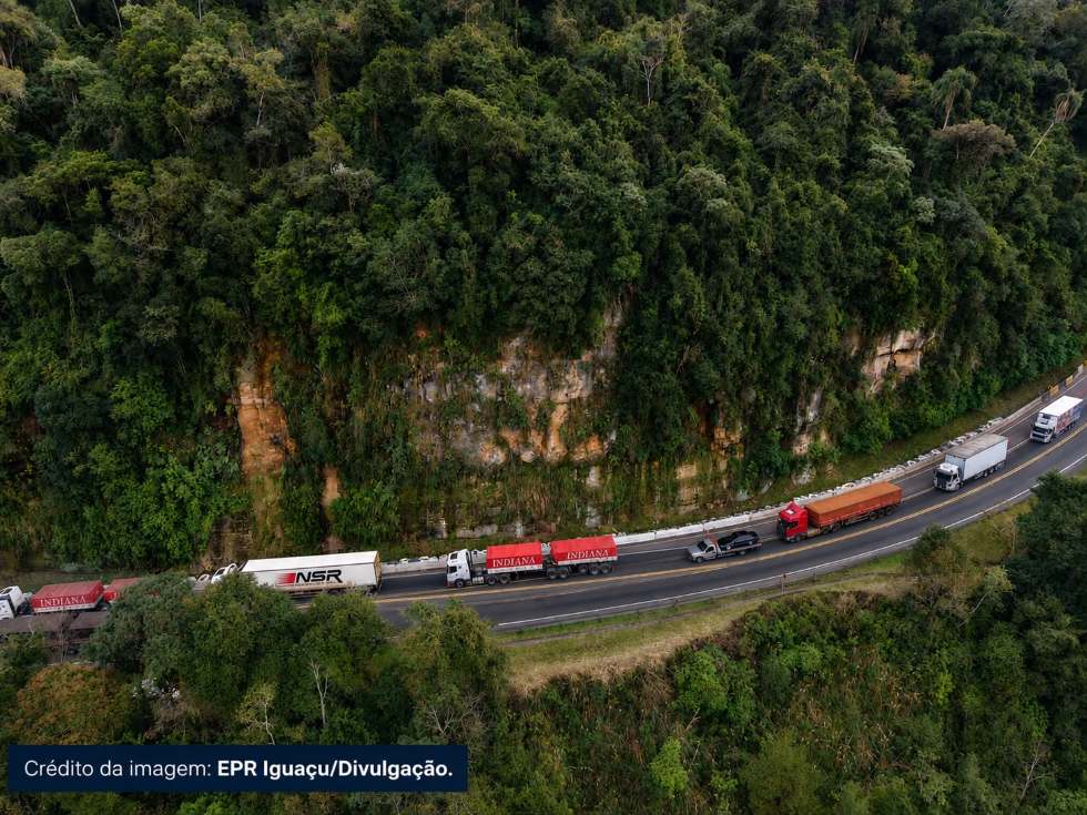 Vista aérea da BR-277, no km 312, na Serra da Esperança, com fila de caminhões ao lado de uma encosta coberta por vegetação.