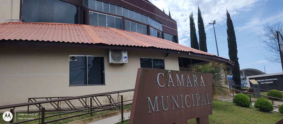 Fachada da Câmara Municipal de Pinhão, com placa de identificação em primeiro plano, rampas de acesso e o prédio ao fundo.