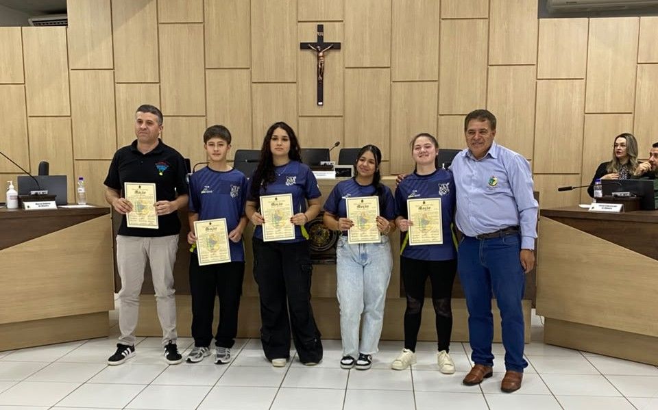 Atletas e professor de xadrez exibem Moções de Congratulações ao lado do vereador Jair Gonçalves, no plenário da Câmara Municipal de Pinhão.