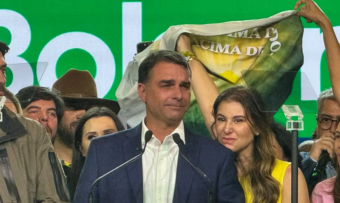 Flávio Bolsonaro discursa emocionado ao lado da esposa, Fernanda Bolsonaro, durante a convenção nacional do PL que oficializou sua candidatura à Presidência da República em 2026.