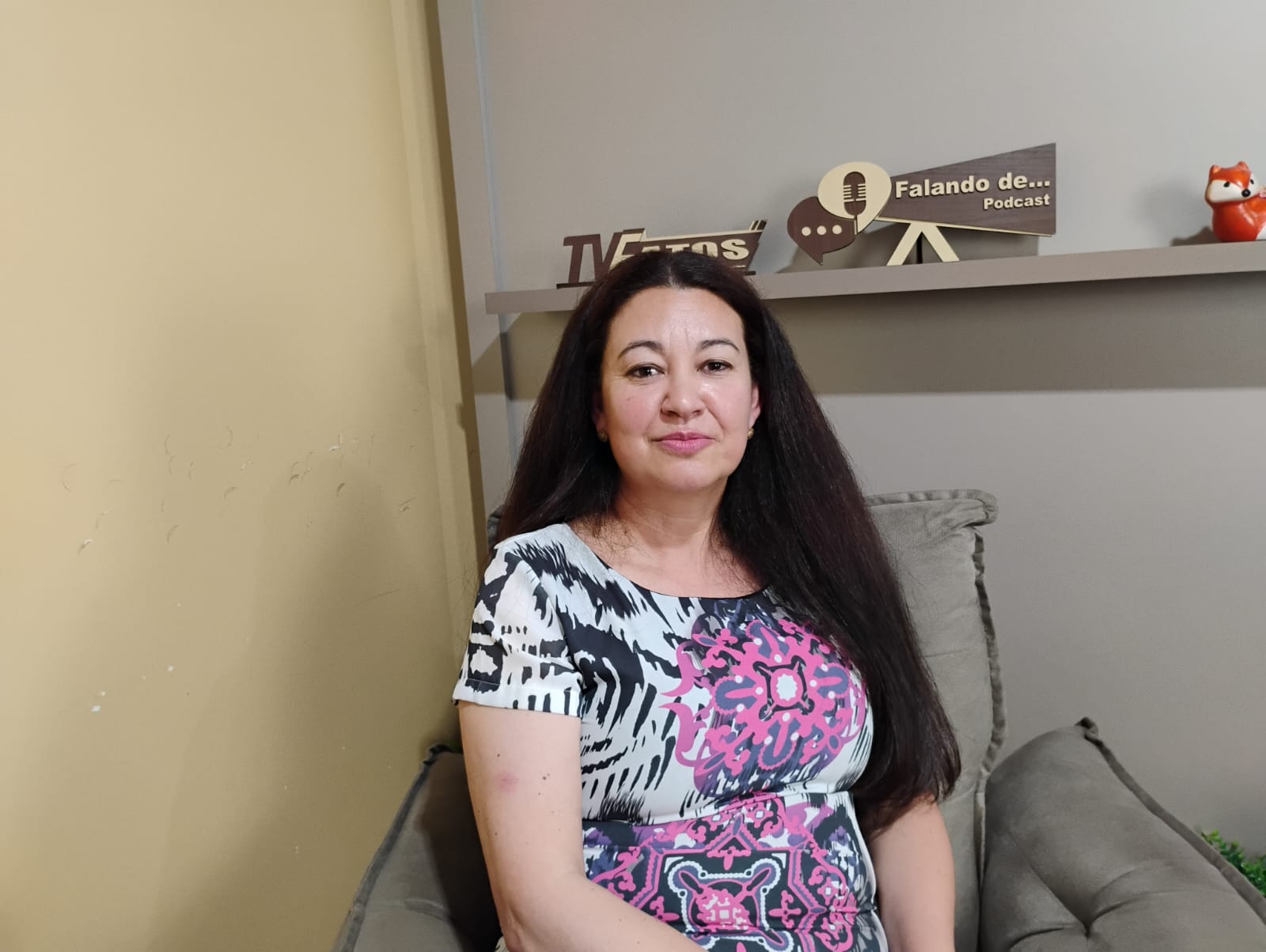 A fisioterapeuta e pesquisadora Ione Rodrigues Correia Woynaroski sentada no estúdio da TV Fatos, com as identificações do canal e do podcast “Falando De...” ao fundo.