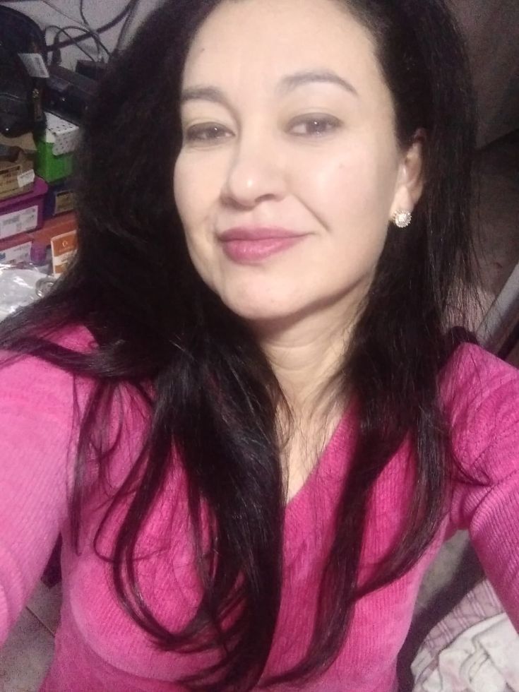 Retrato de Ione Rodrigues Correia Woynaroski, com cabelos longos e escuros, usando blusa rosa e olhando para a câmera.
